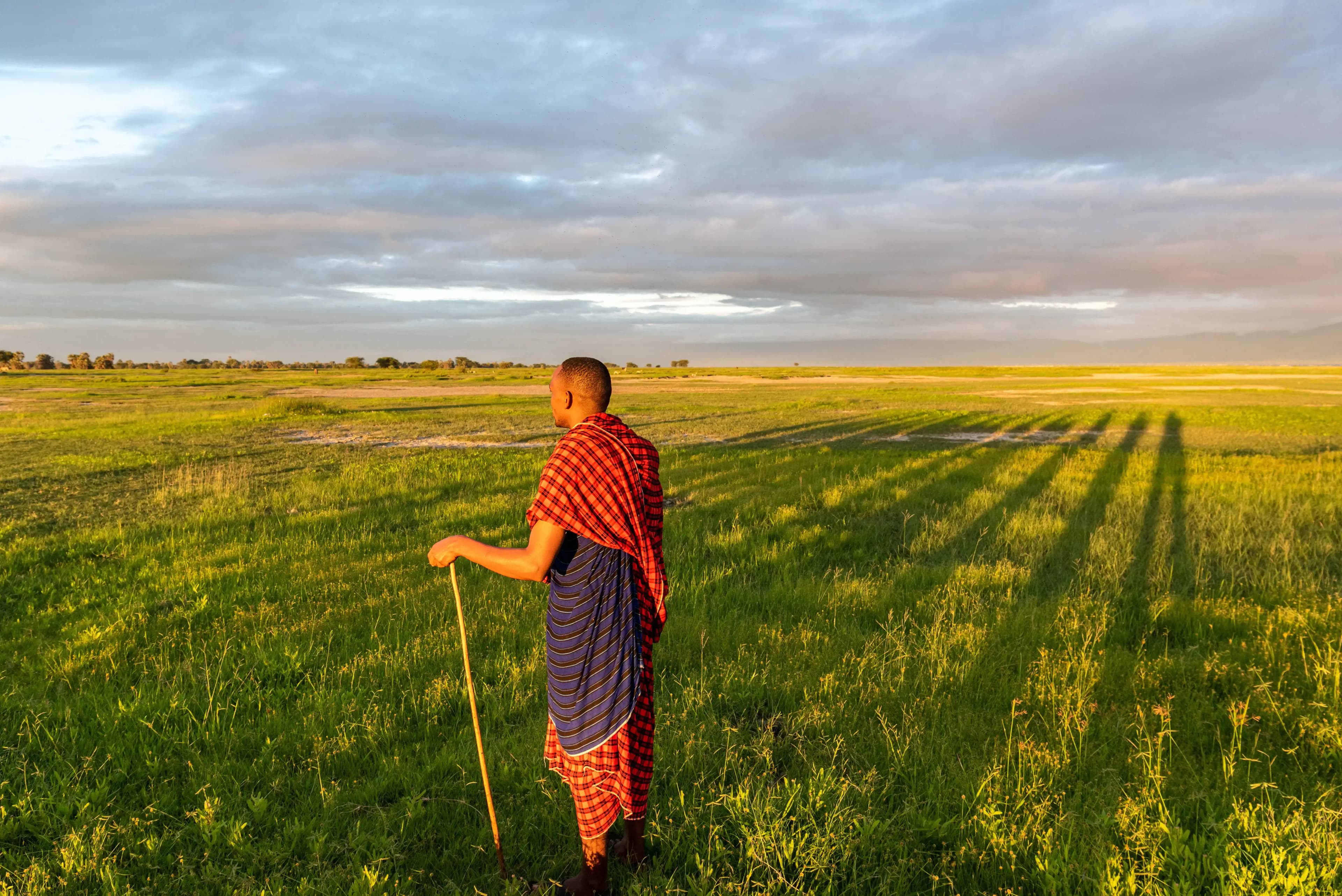 A Maasai person silhouetted against a vibrant sunset